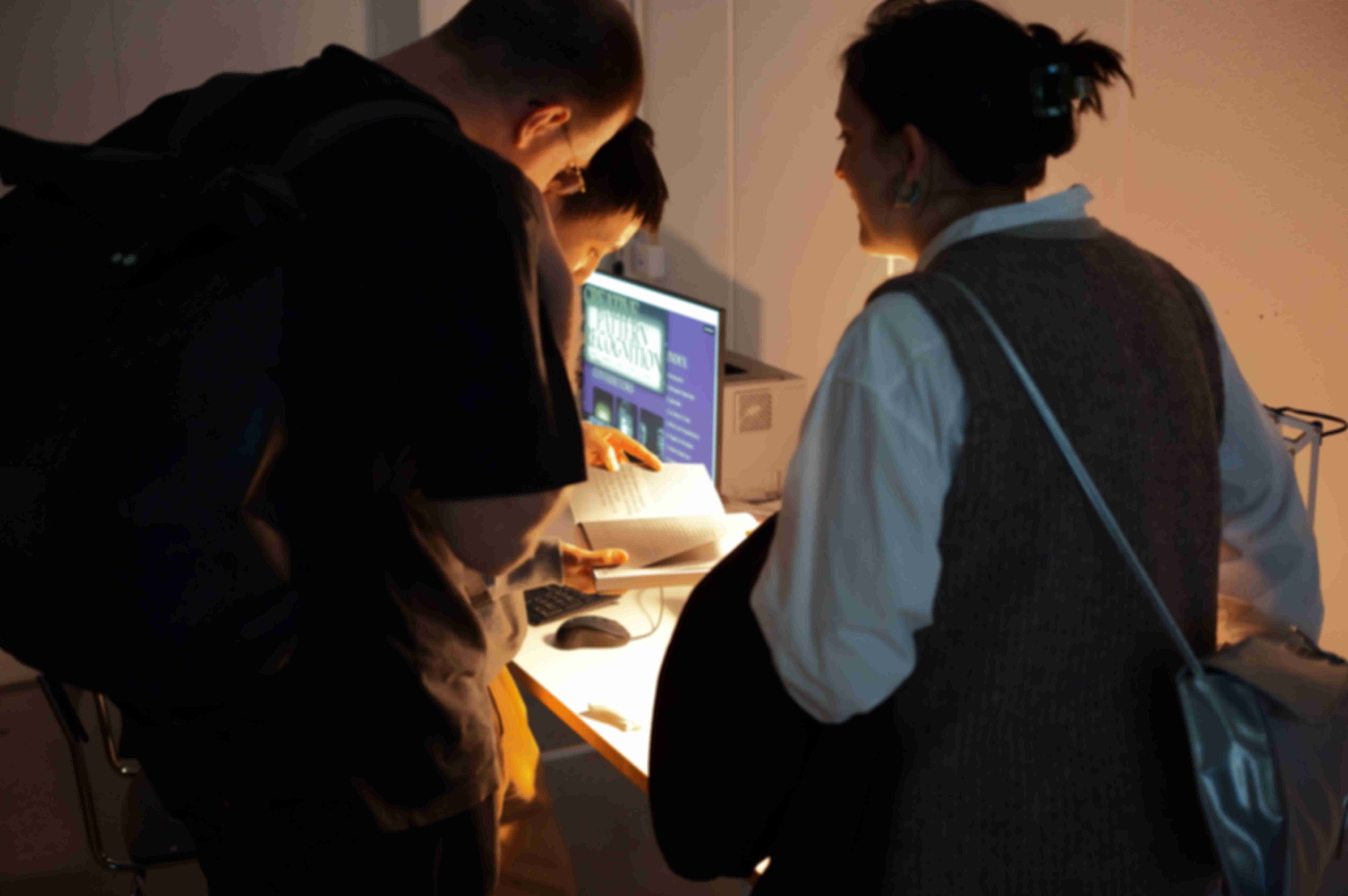 Three people looking at the broschure of Creative Pattern Recognition during the exhibition "What will be there in the end?"