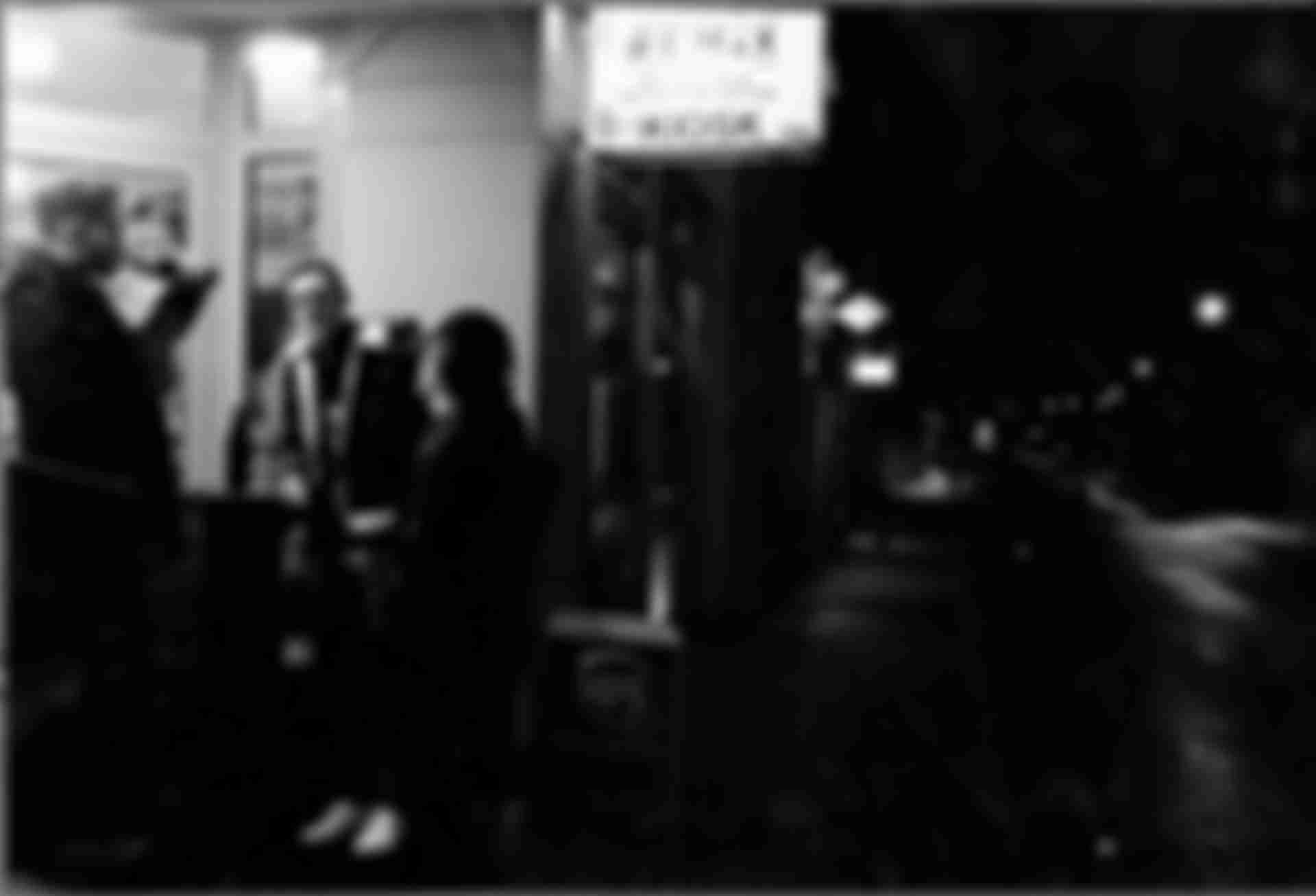 A group of young people in front of a kiosk illuminated by a shop sign.