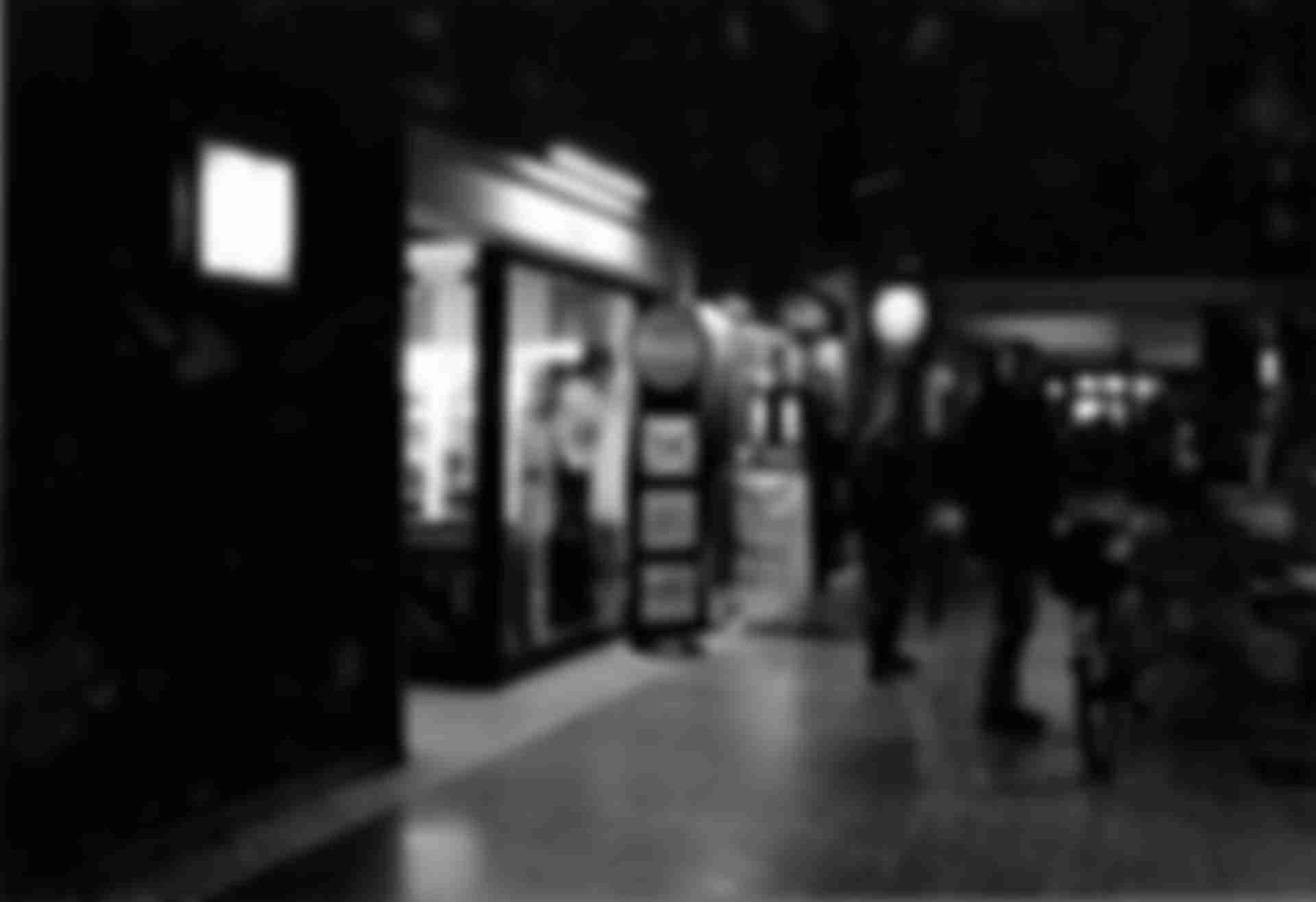 A kiosk in a passage illuminated by neon tubes.