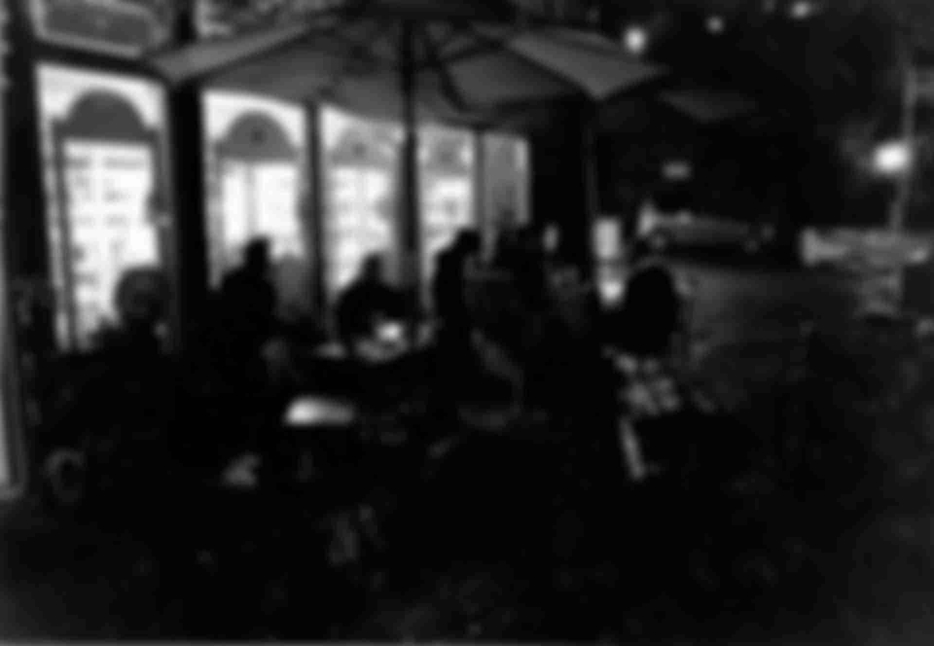 Groups of people sitting in front of a kiosk at tables.